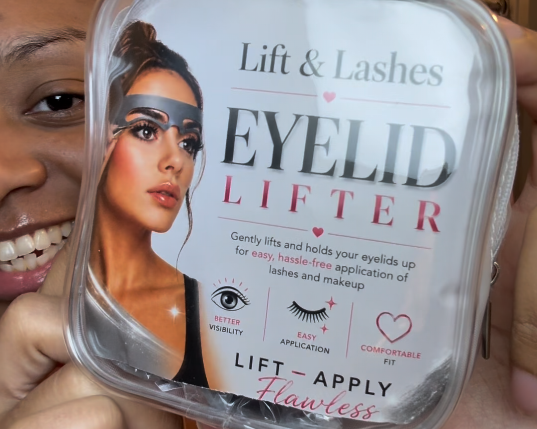 A person holds a square clear plastic container of Lift & Lashes Eyelid Lifter against a mirror, with the product label facing forward. The label shows a woman's face with eyelashes enhanced, and the text reads 'Lift & Lashes EYELID LIFTER' with 'LIFT - APPLY Faceless'.
